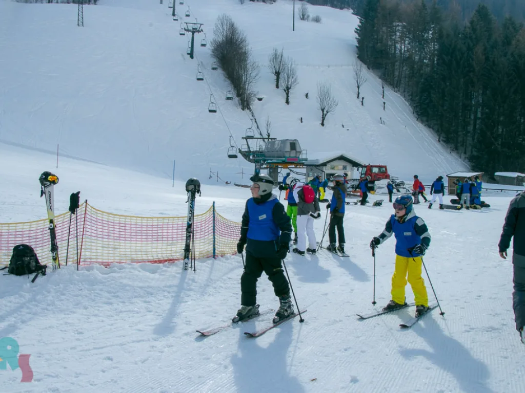 Skifahrende am Pistenrand vor dem Sessellift.